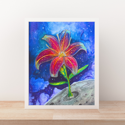 Framed artwork of a colorful flower with a space-themed background on a wooden surface.