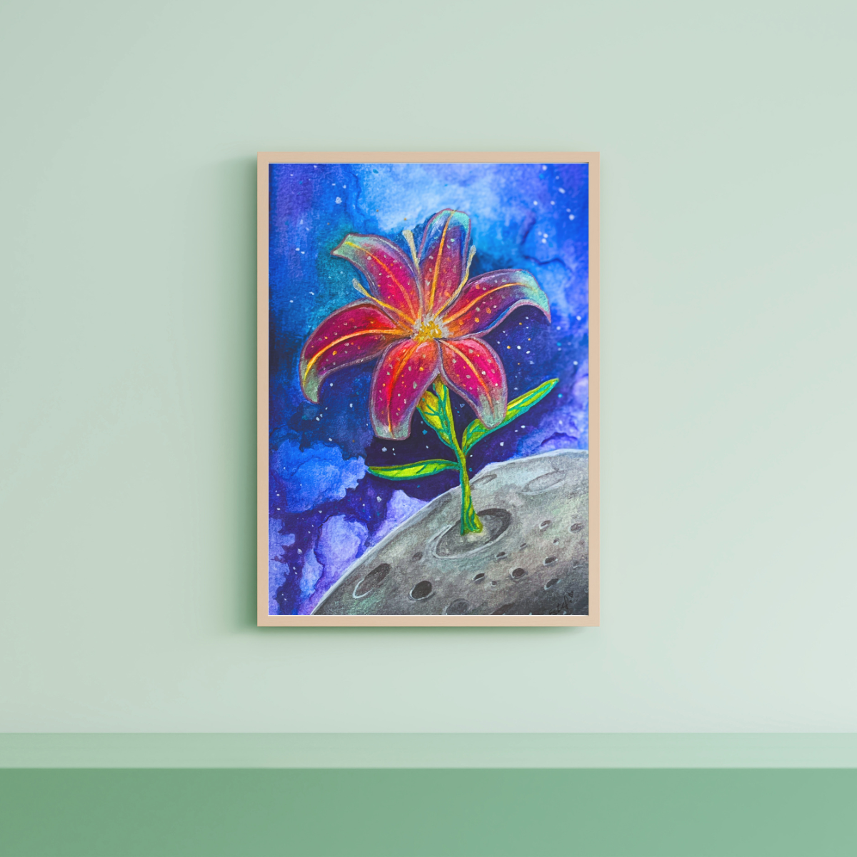 Framed artwork of a colorful flower on a celestial background, displayed on a light green wall.