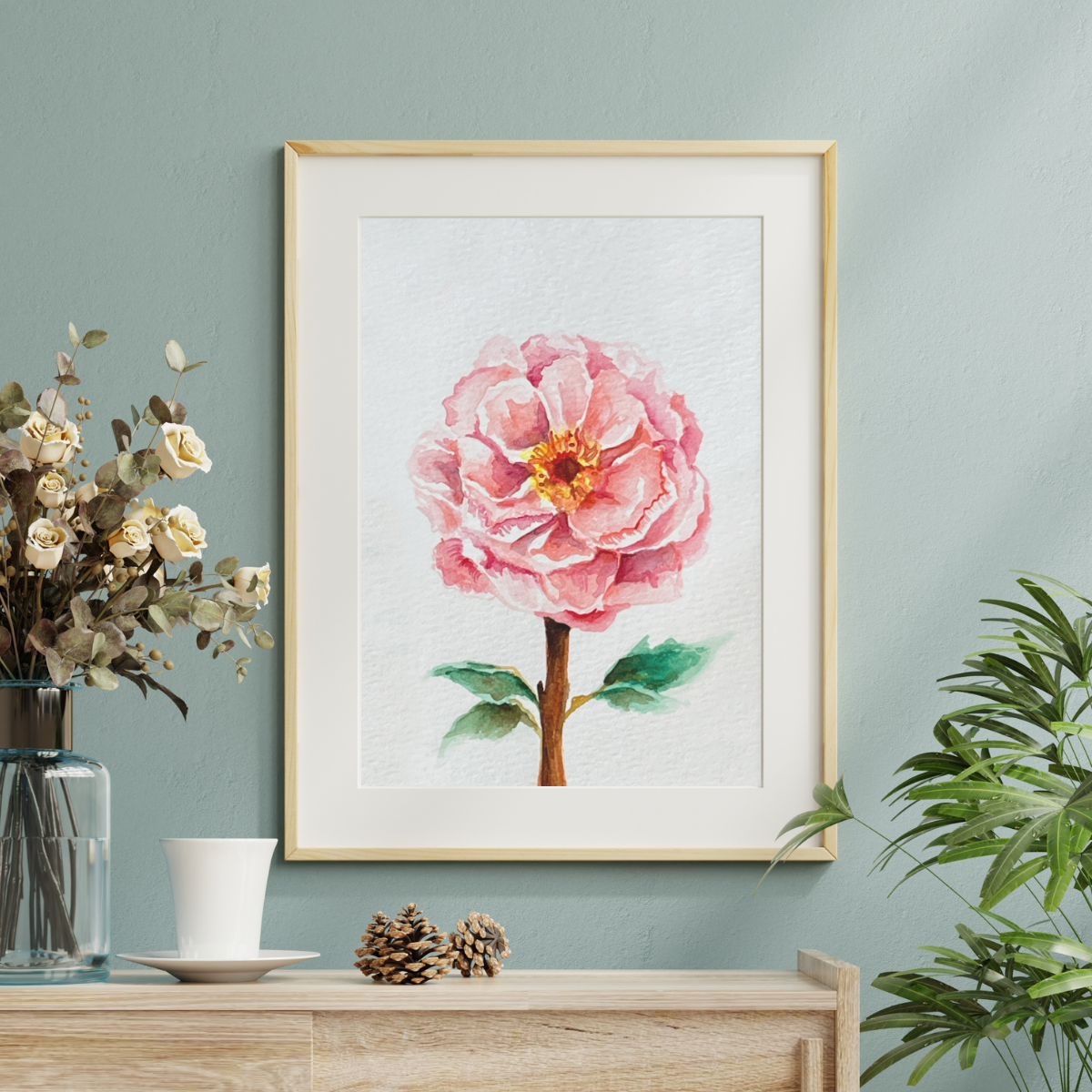 Framed artwork of a pink flower on a wall with decorative items below.