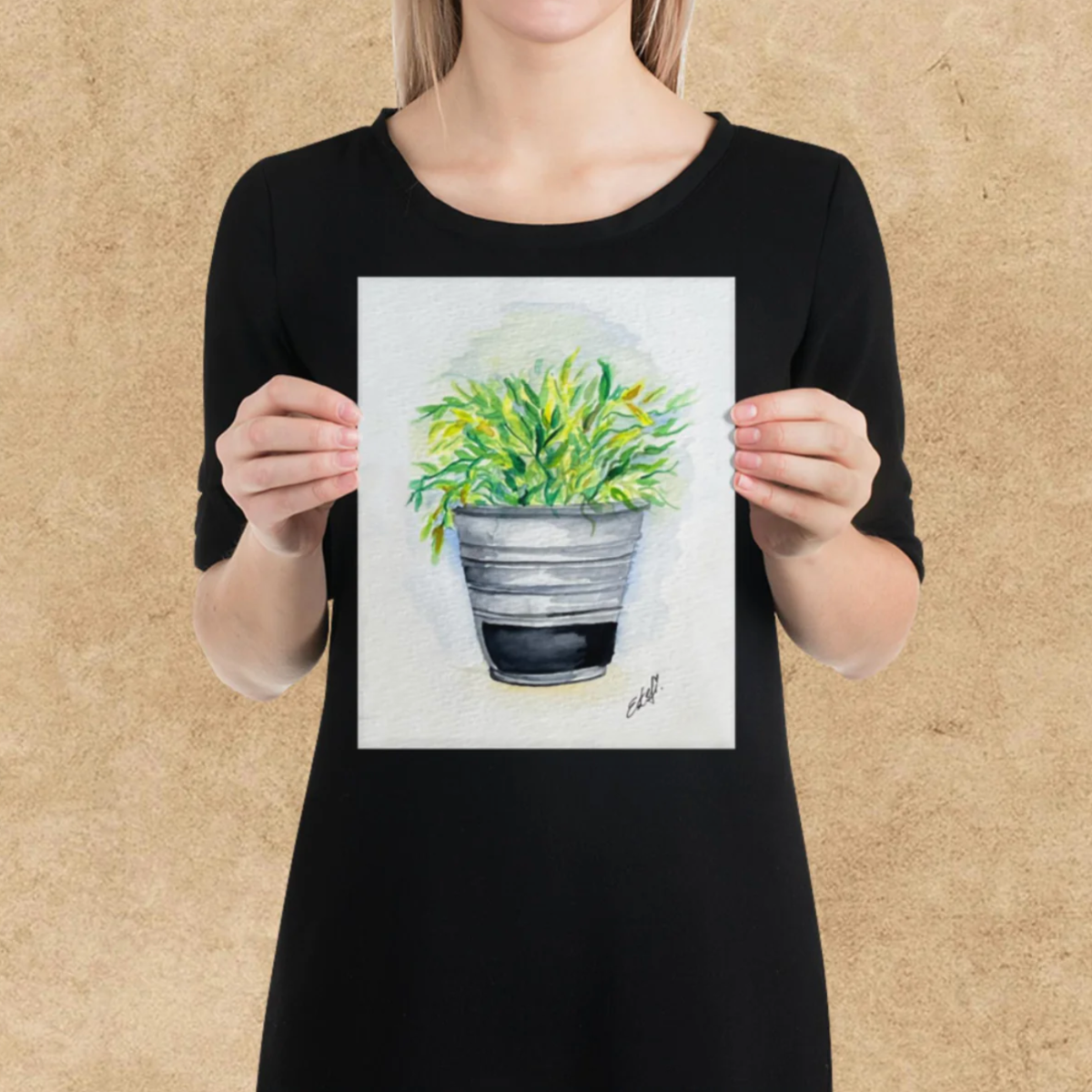 Person holding a drawing of a potted plant against a beige background