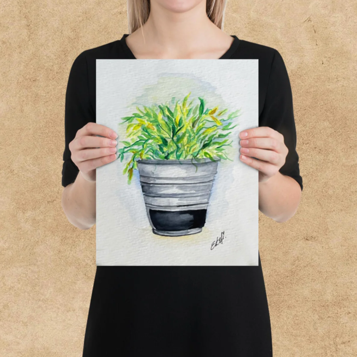 Person holding a painting of a potted plant against a beige background